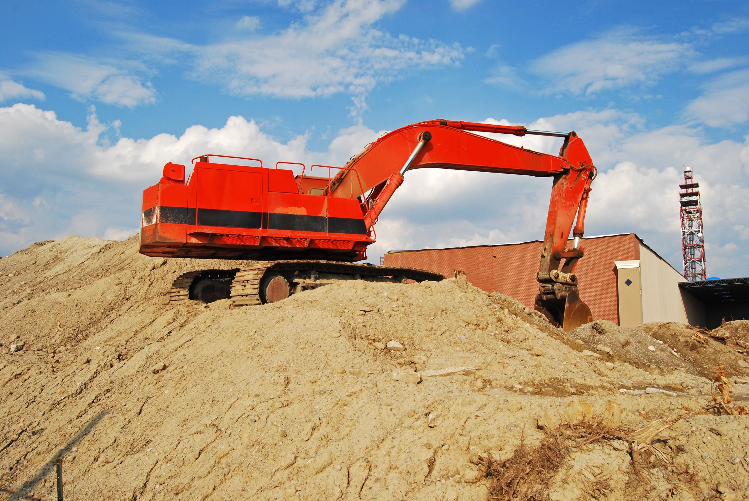 crane on a large pile of clay dirt